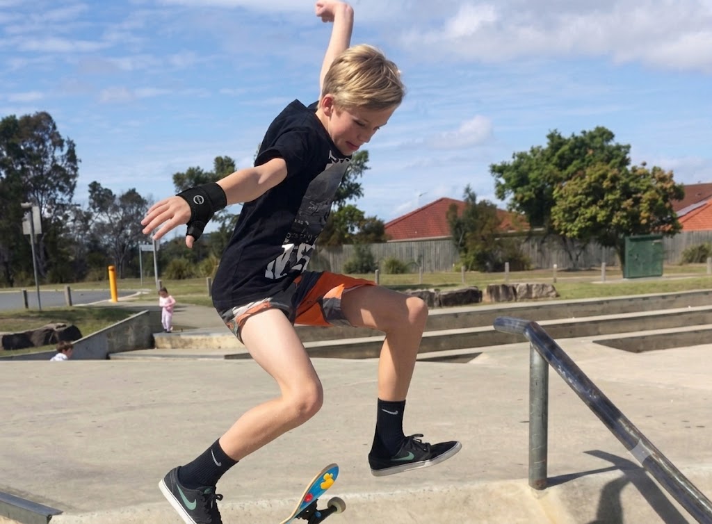 a skateboarder doing an ollie wearing a cast on their arm and a black t-shirt
